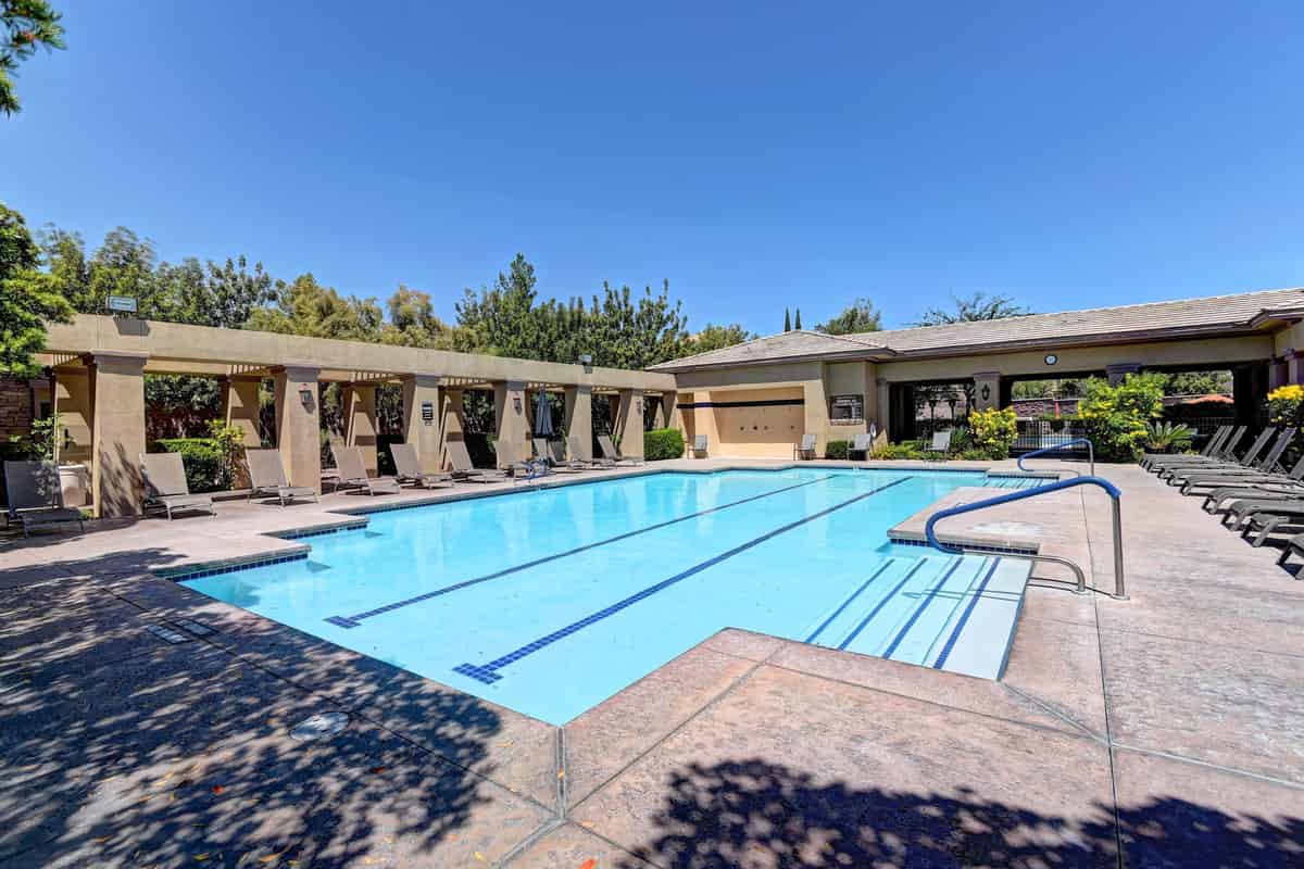 a swimming pool with lounge chairs and trees