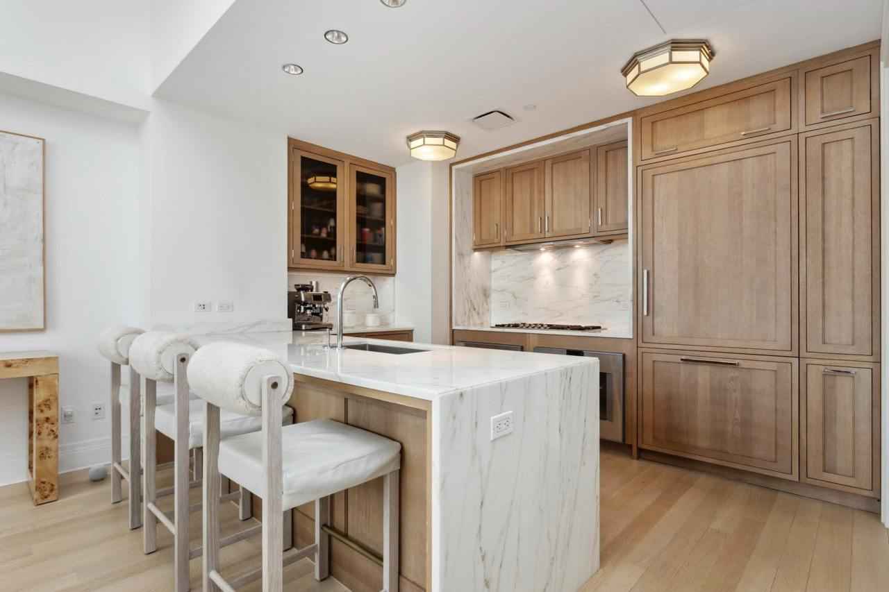 a kitchen with a marble island and wooden cabinets