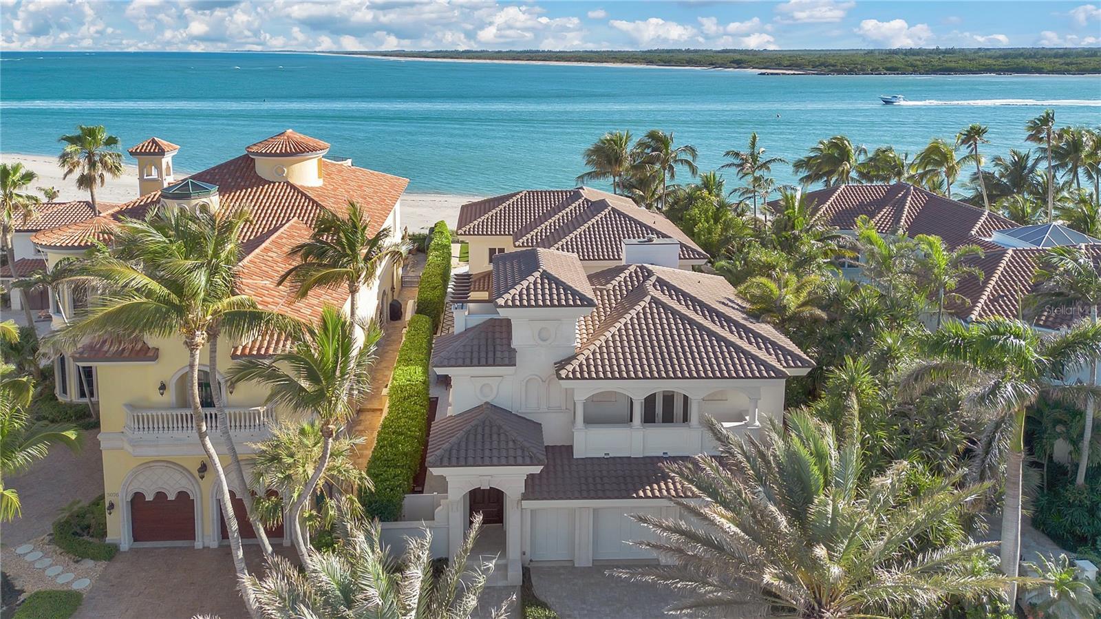 a large home with palm trees and a beach in the background
