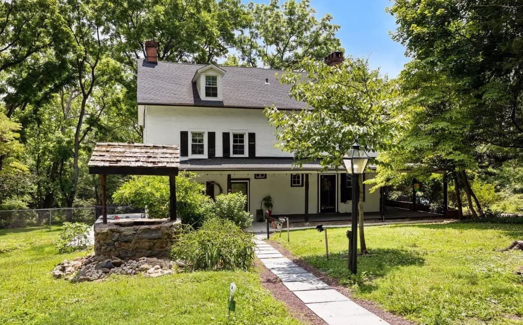 a white house with a black roof and a stone walkway
