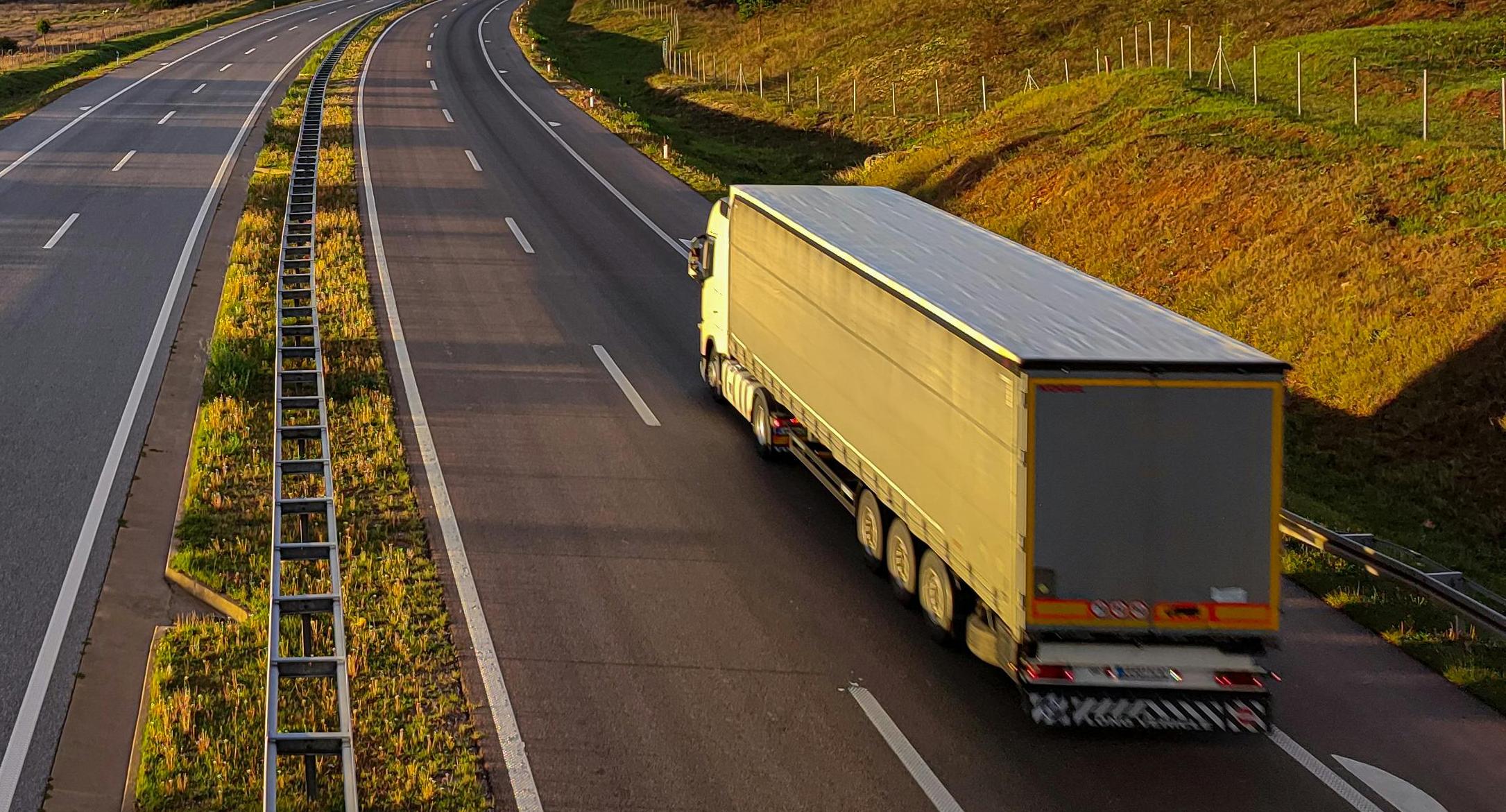 Long-haul moving truck driving on a highway, representing the scale and logistics of the U.S. moving industry.